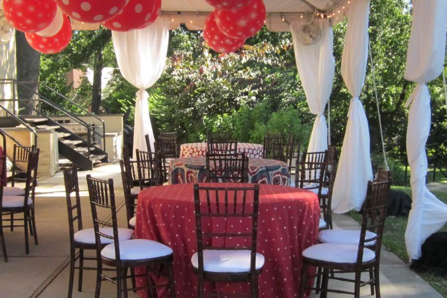 Tented patio party with draped columns, balloons and red linens