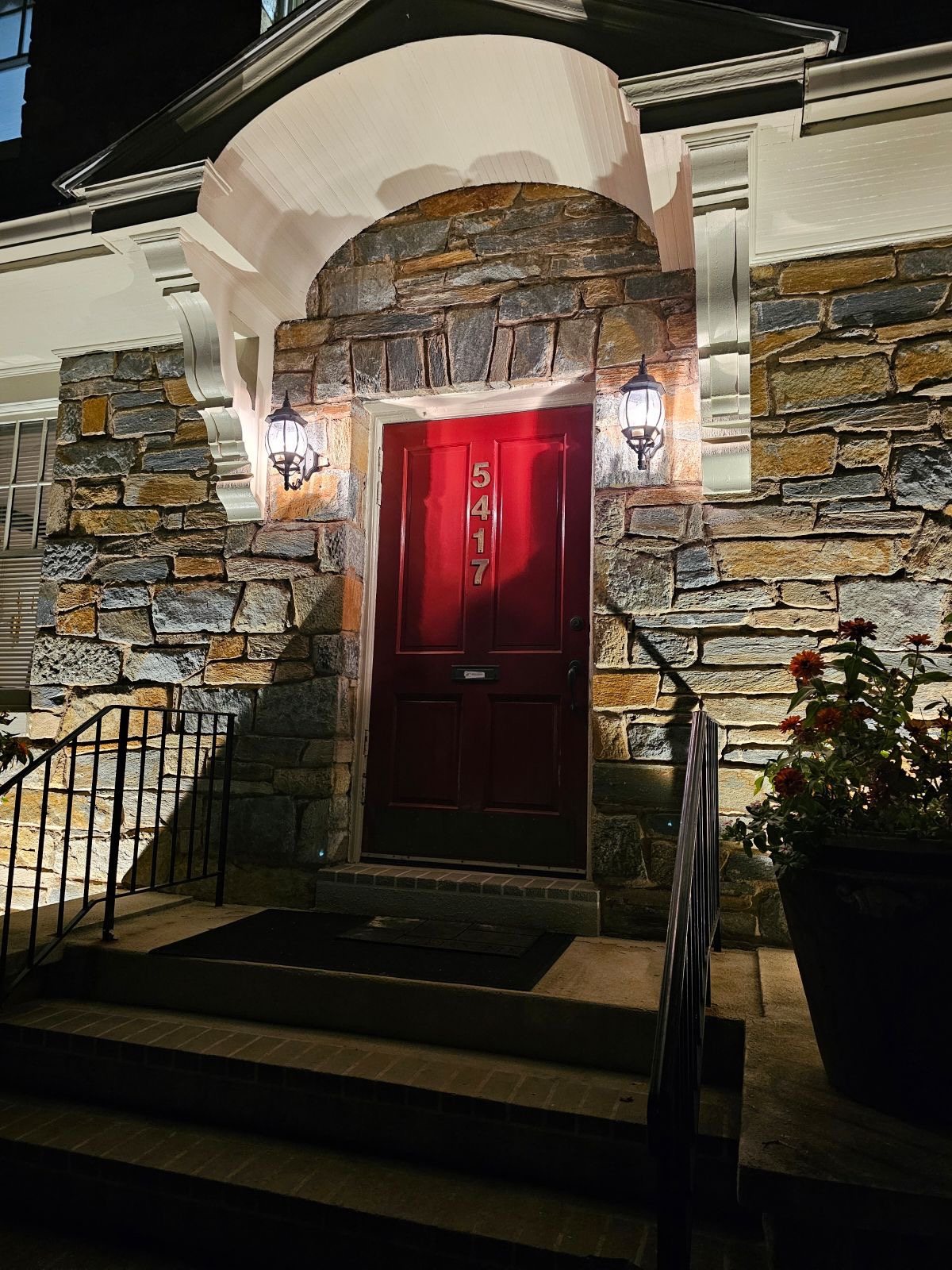 The mansion's stone archway and red front door at night