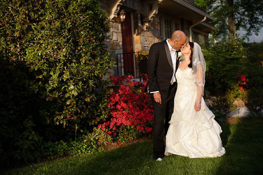 Bride and groom on the mansion grounds beside flowering azaleas